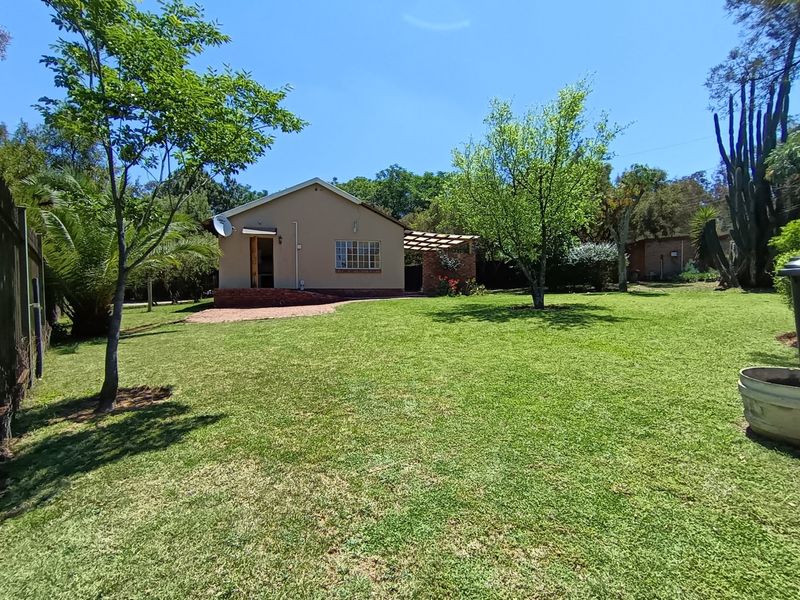 Rear view of the house featuring a spacious lawn, a brick patio area, and a timber pergola structure.