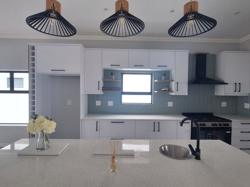 Modern kitchen featuring a central island with quartz countertops, sleek white cabinetry, a gas stove with extractor fan, and stylish pendant lighting.