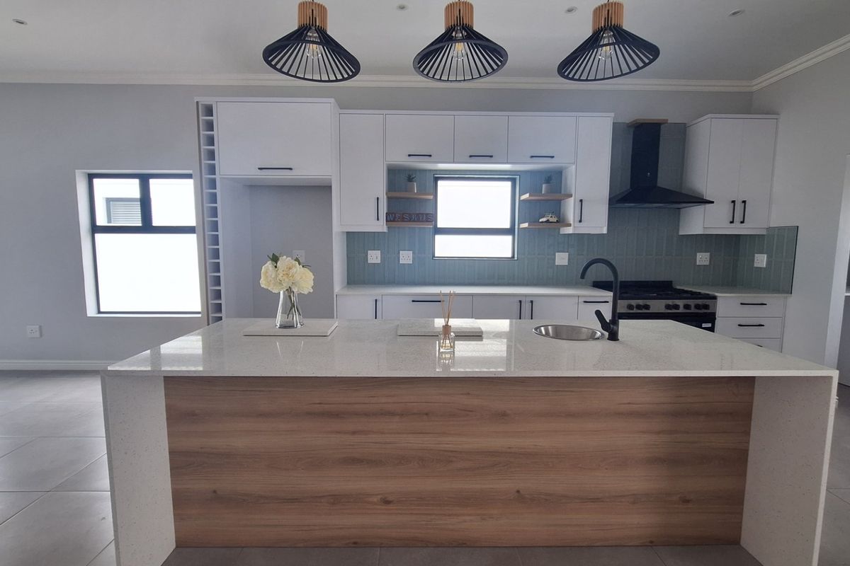 Modern kitchen featuring a central island with quartz countertops, sleek white cabinetry, integrated gas hob, extractor fan, and stylish pendant lighting.