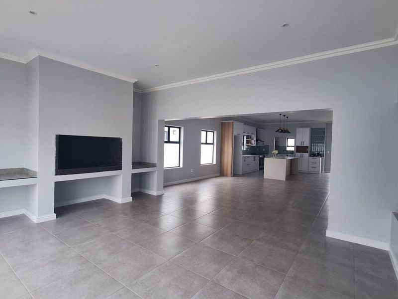 Spacious open-plan living area featuring large format floor tiles, a built-in fireplace, and a modern kitchen with a central island.
