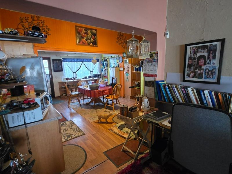 An open-plan living and dining area featuring hardwood flooring and coved ceilings, offering a versatile layout with potential for modernization.