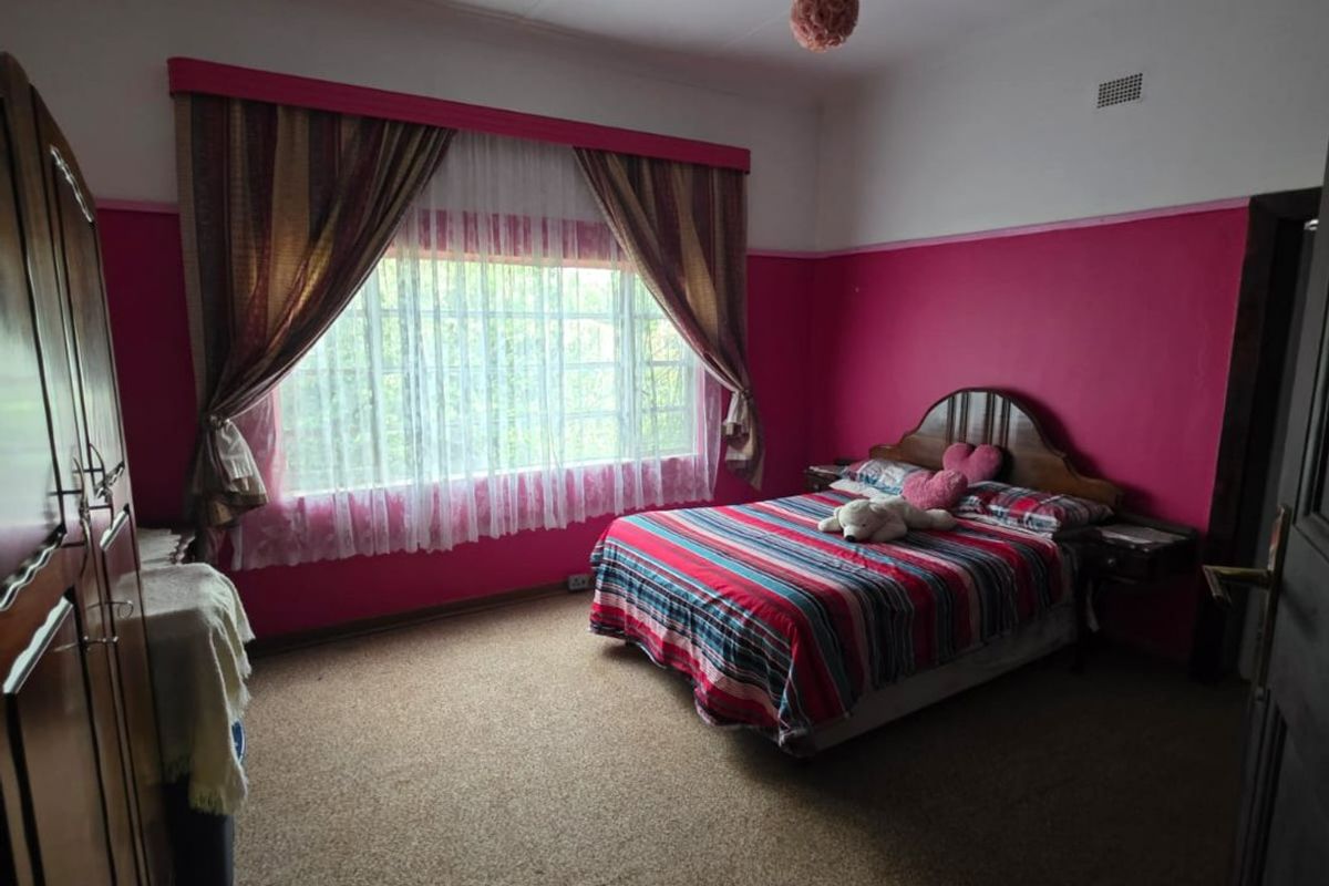 A bedroom featuring carpet flooring, a ceiling fan, and built-in wardrobe storage, currently finished with dated wall paint.
