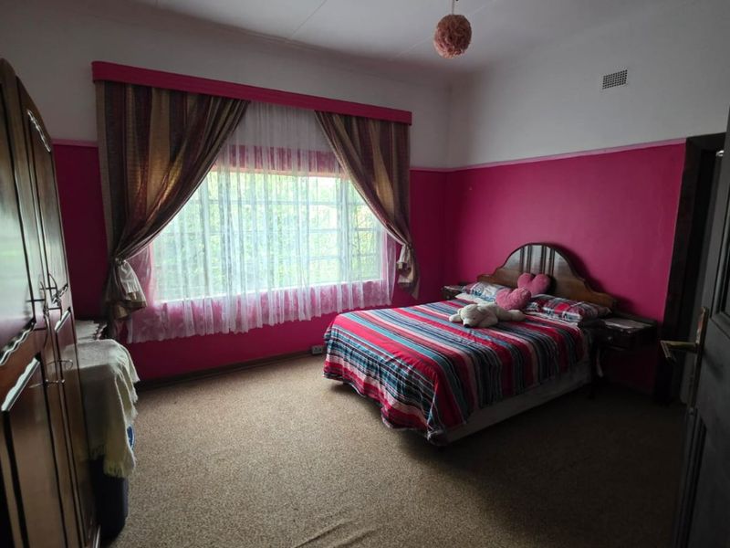 A bedroom featuring carpet flooring, a ceiling fan, and built-in wardrobe storage, currently finished with dated wall paint.