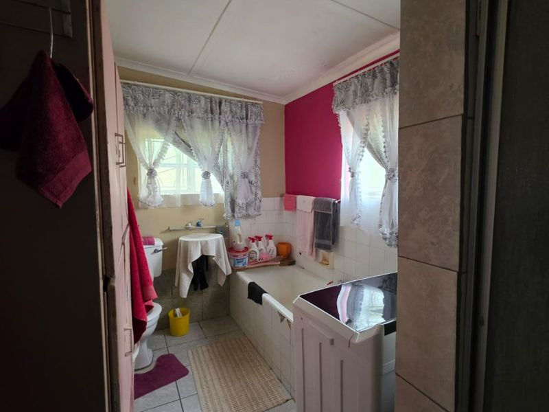 A functional bathroom featuring a bathtub, toilet, and tiled flooring, currently showing signs of age and in need of cosmetic updates.