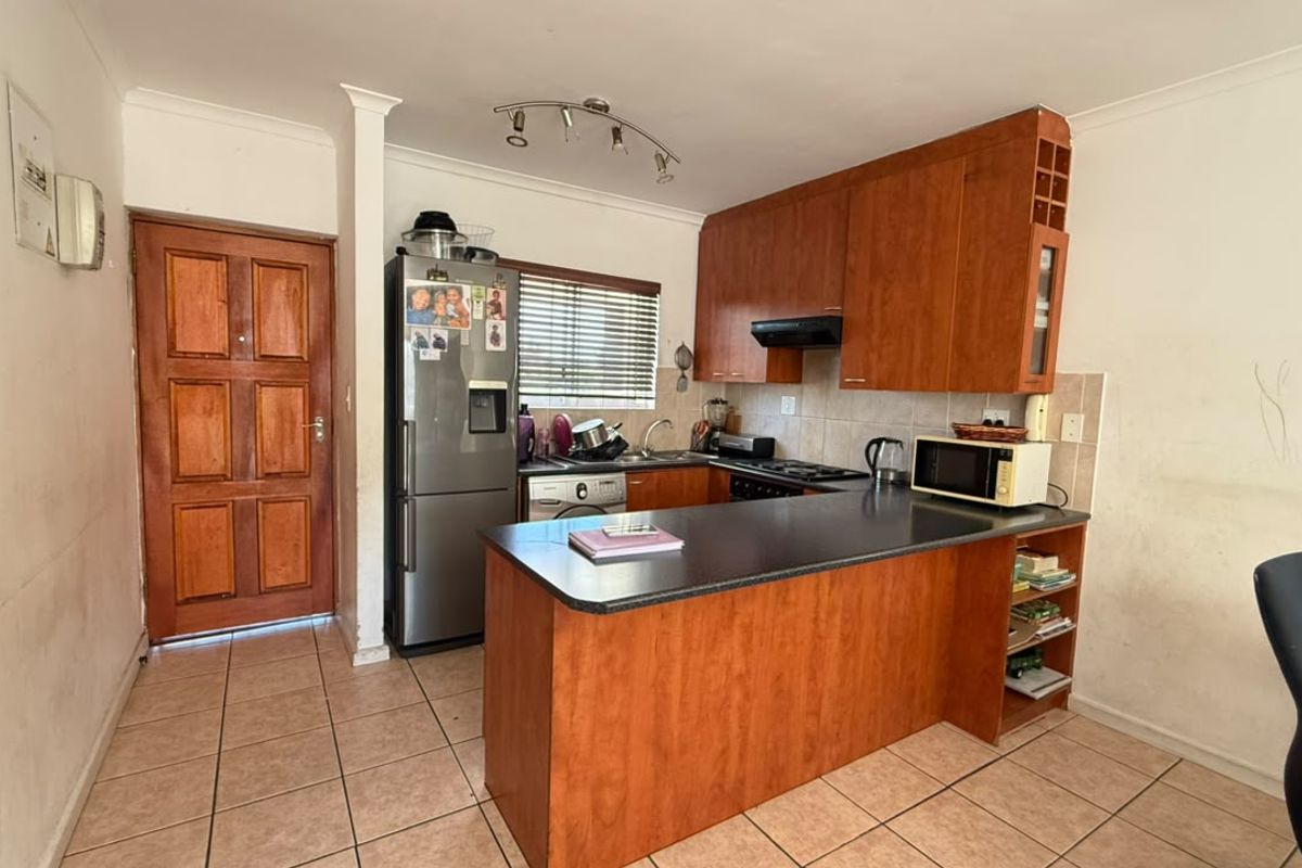 Functional kitchen featuring wood-look cabinetry, dark laminate countertops, tiled flooring, and integrated cooking appliances, offering a practical layout for daily use.