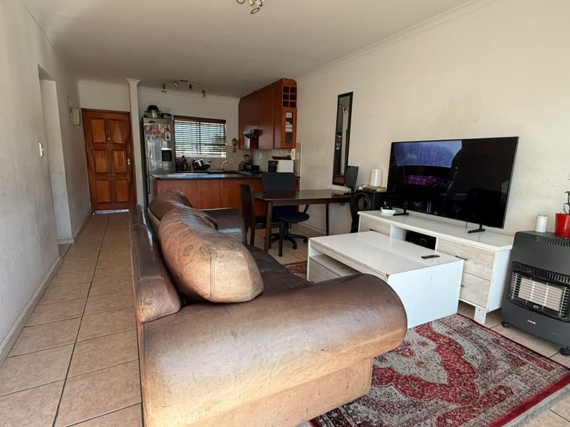 Open-plan living and kitchen area featuring tiled flooring, timber cabinetry, and direct access to the main entrance.