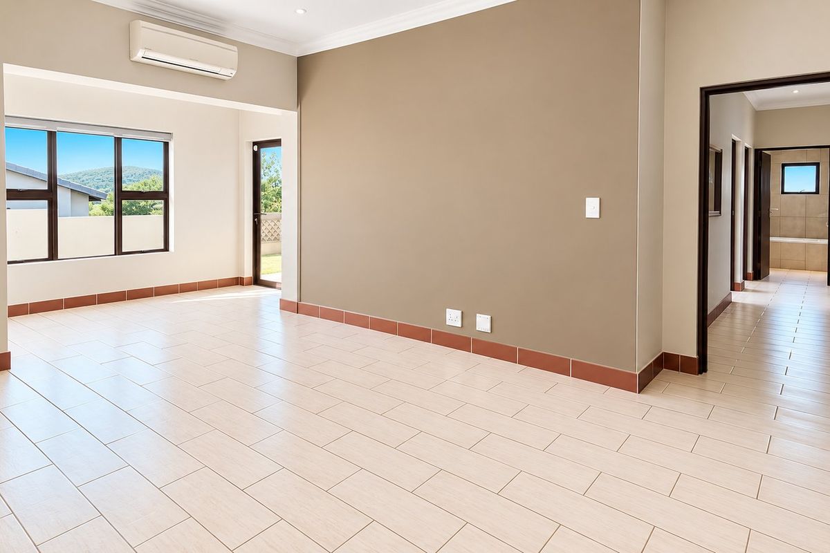 A spacious, light-filled living area featuring neutral tones, tiled flooring, and a split-system air conditioner, offering a clean and versatile space.