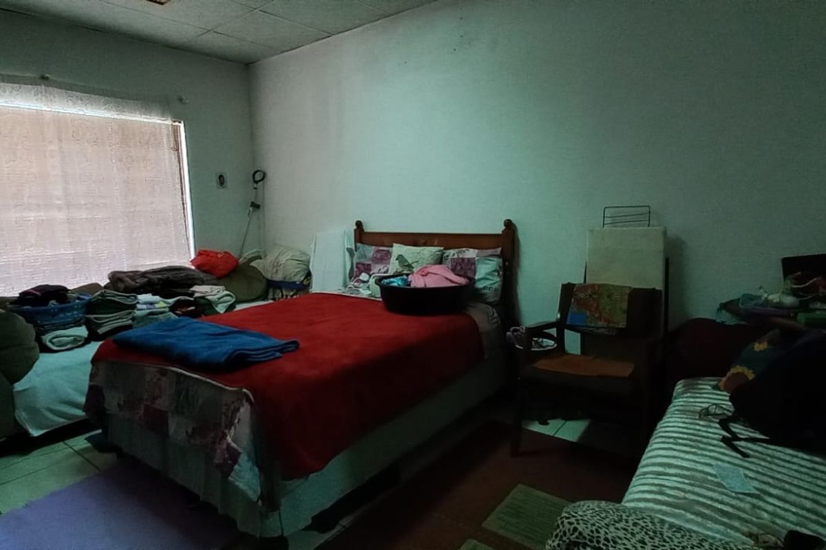 A bedroom featuring tiled flooring and a large window, currently requiring cosmetic updates to the ceiling and wall finishes.