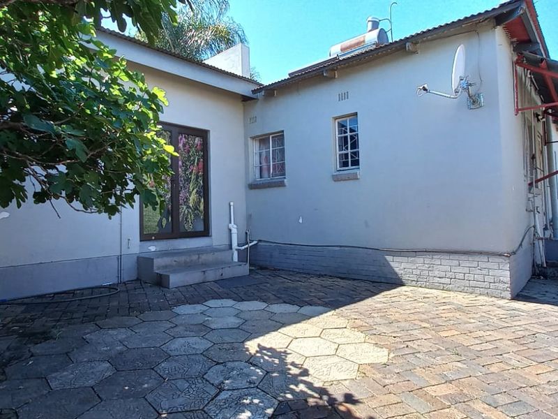 Rear exterior view of the property featuring a paved patio area, solar water heater, and metal roof awning.