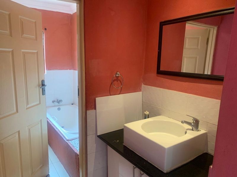A dated bathroom featuring a vessel sink on a granite vanity, a separate bathtub area, and walls requiring cosmetic updates.