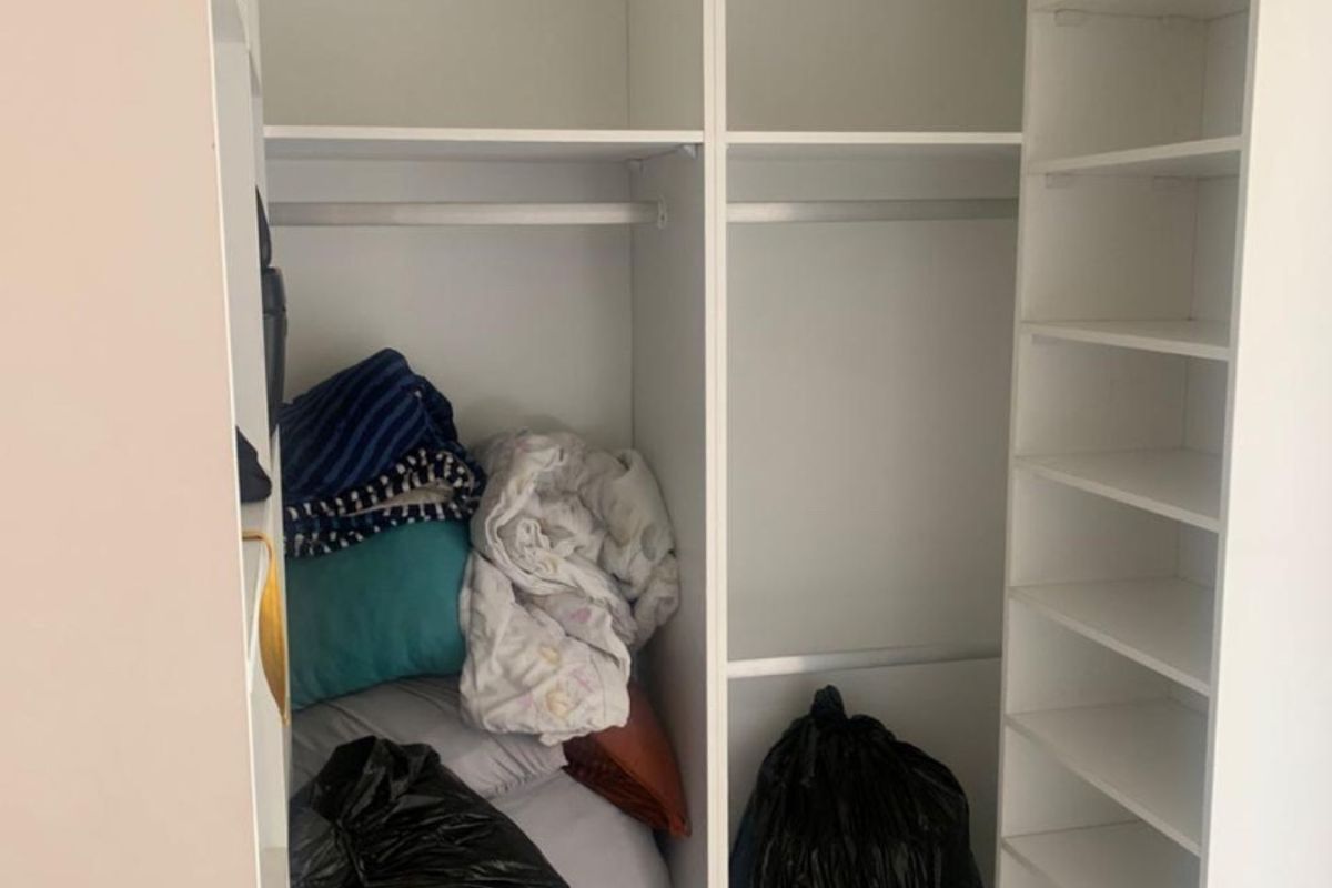 A built-in bedroom wardrobe featuring multiple storage shelves and hanging rails for organized clothing storage.
