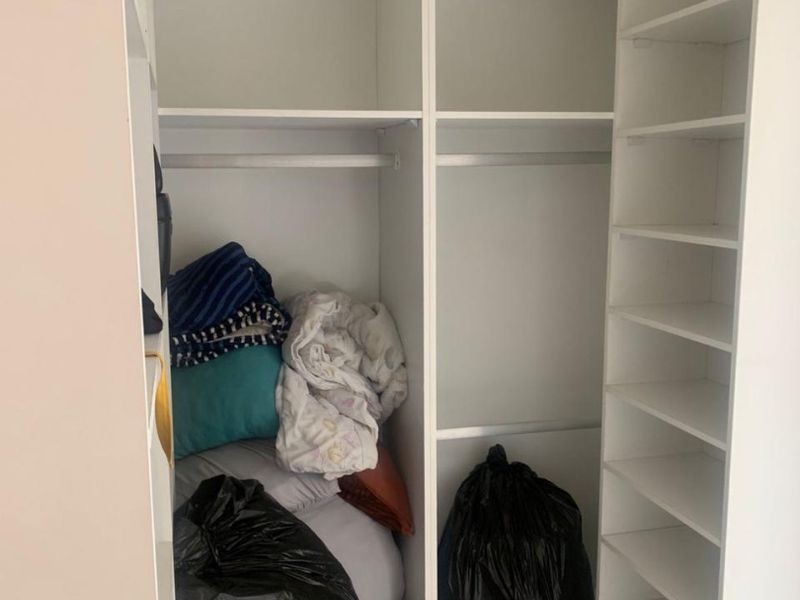 A built-in bedroom wardrobe featuring multiple storage shelves and hanging rails for organized clothing storage.