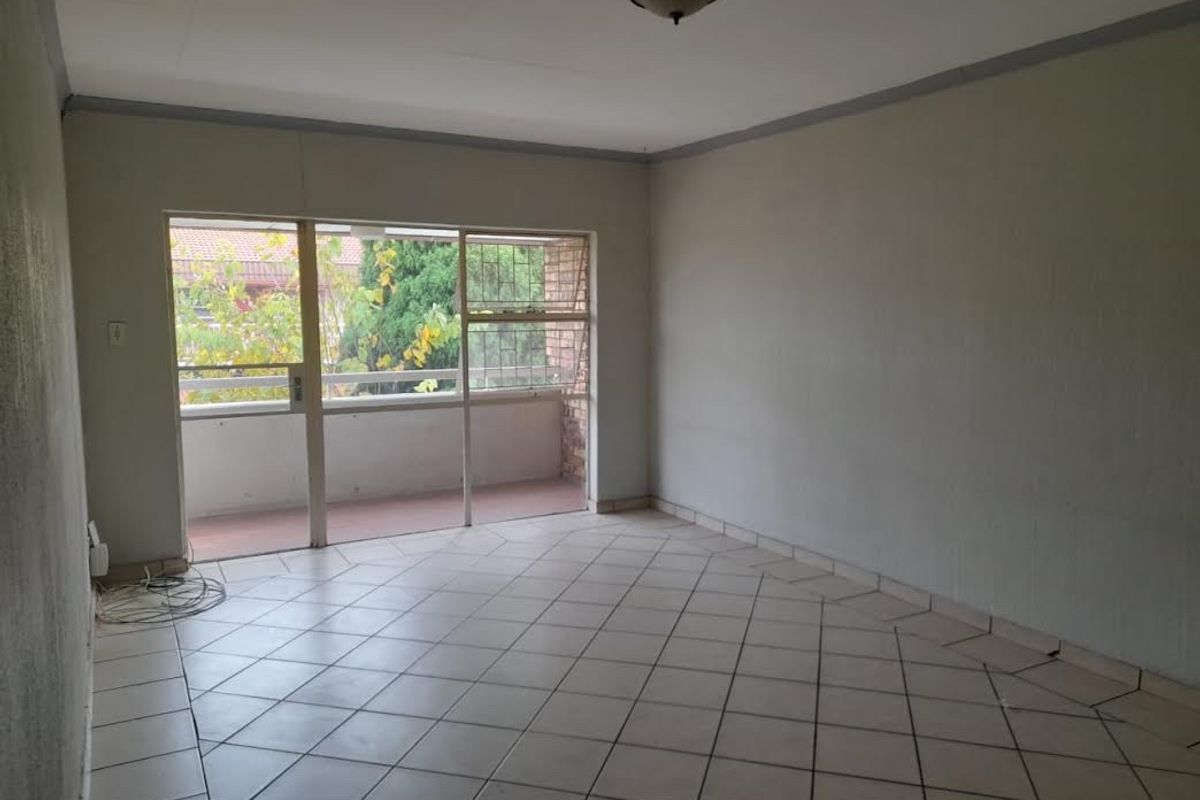 An empty living room featuring tiled flooring and a large sliding glass door providing access to an outdoor balcony area.