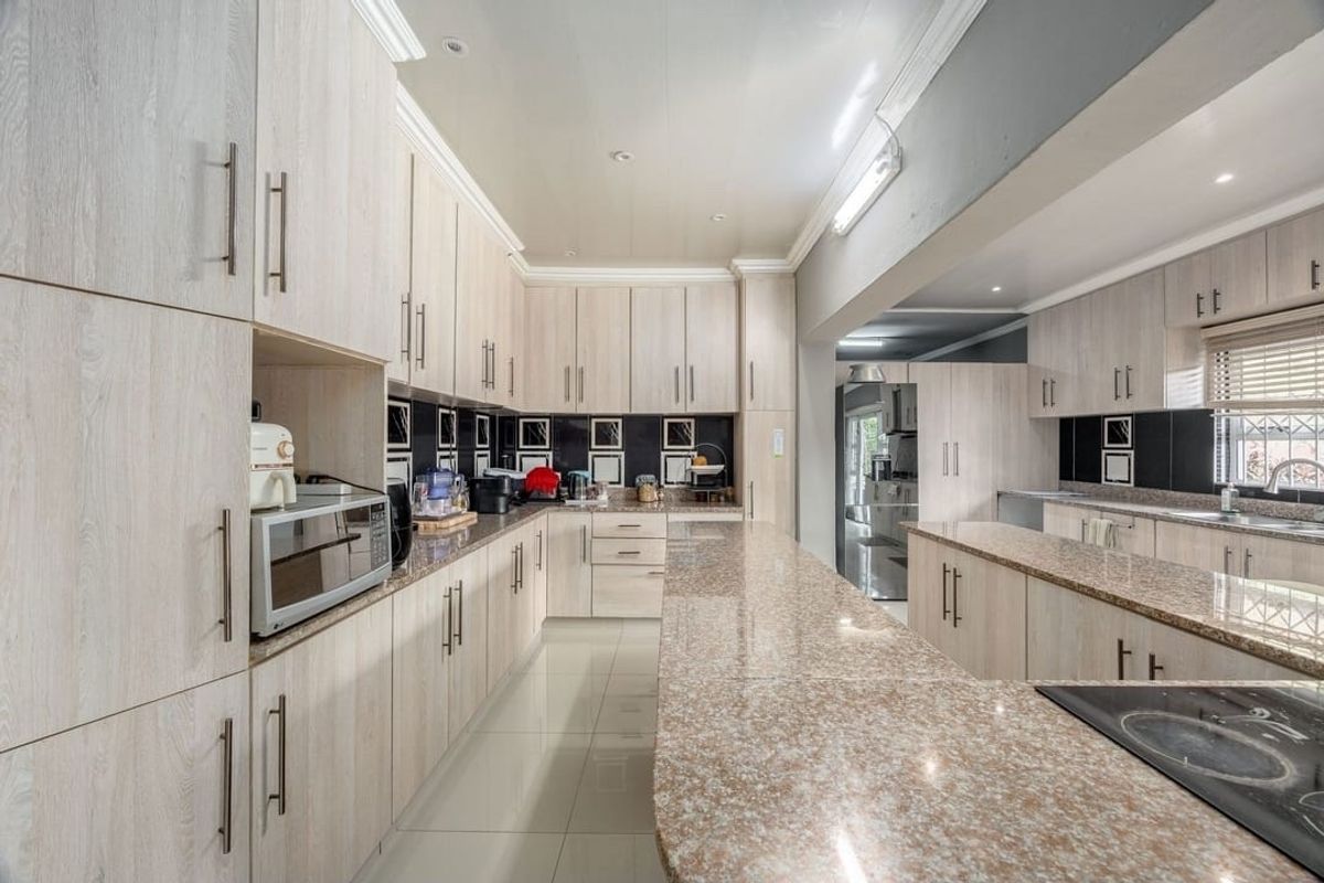 Spacious kitchen featuring extensive light wood cabinetry, granite countertops, ceramic tile flooring, and a functional layout with ample storage and workspace.