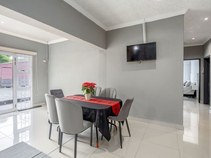 A bright dining area featuring polished tiled flooring, recessed ceiling lighting, and a sliding glass door providing access to the exterior.