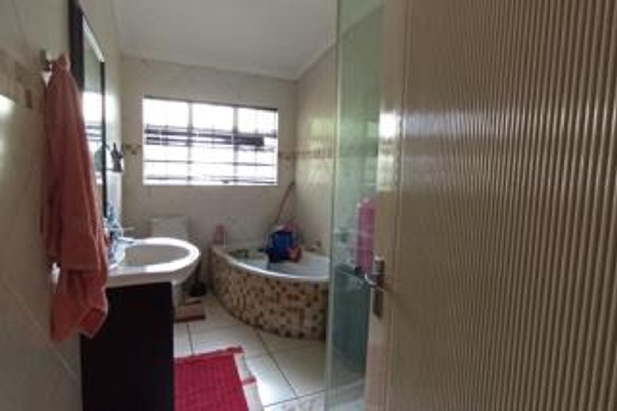 A functional bathroom featuring a pedestal basin, a built-in bathtub with tiled surround, and a separate glass-enclosed shower area.