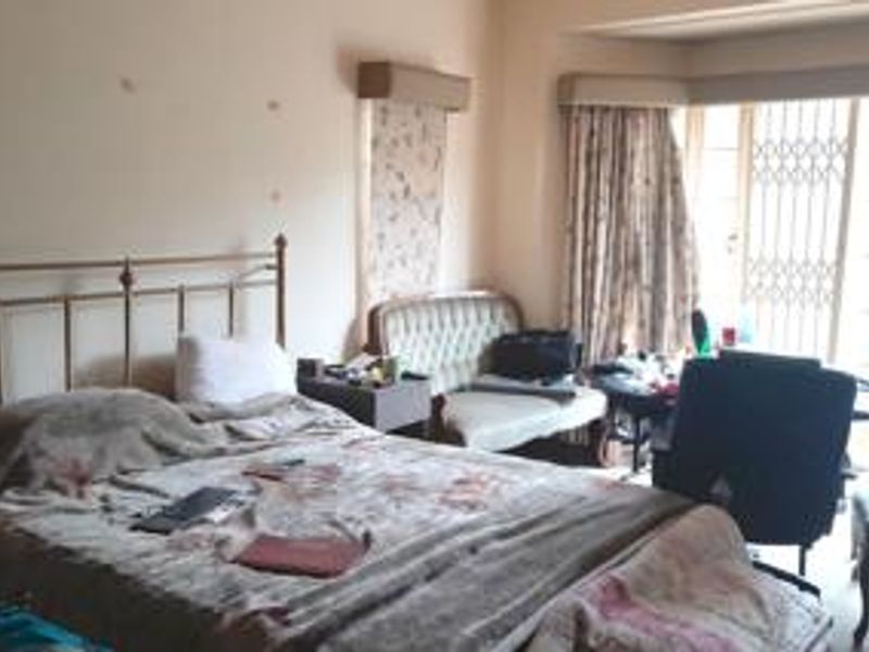 A bedroom featuring a security gate on the window and a curtain pelmet, requiring cosmetic updates to the wall surfaces.