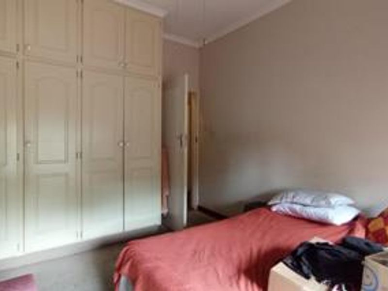 A bedroom featuring floor-to-ceiling built-in cupboards and neutral wall finishes, providing ample storage space.