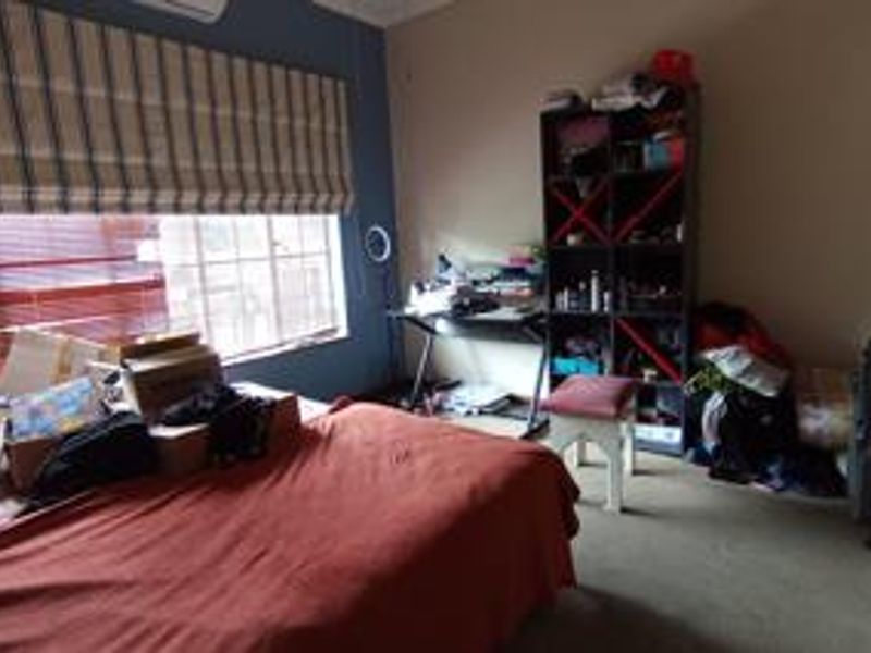 A bedroom featuring carpet flooring, a split-system air conditioner, and window blinds, providing a functional space for rest.
