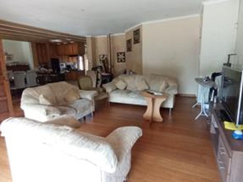 Open plan living and dining area featuring laminate flooring and recessed lighting, with an adjacent kitchen space visible in the background.