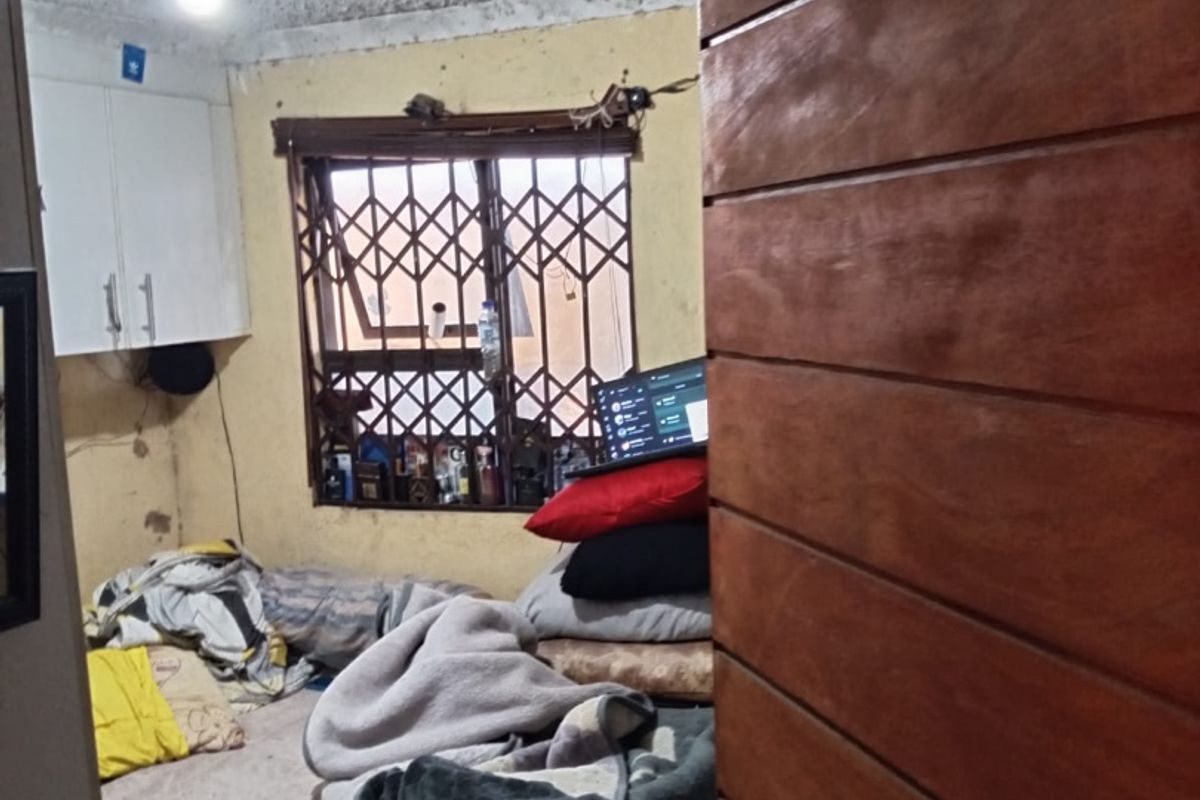 A bedroom featuring a textured ceiling, built-in cabinetry, and a security gate on the window, requiring cosmetic updates and repairs to walls and ceiling.