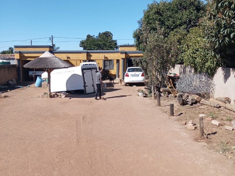 Rear exterior view of the commercial property featuring a large unpaved yard area and access to the garage structure.