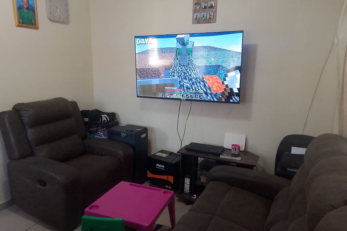 A living room area featuring tiled flooring and a wall-mounted television.