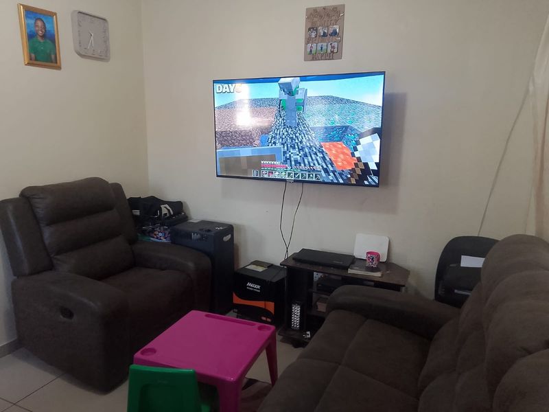 A living room area featuring tiled flooring and a wall-mounted television.