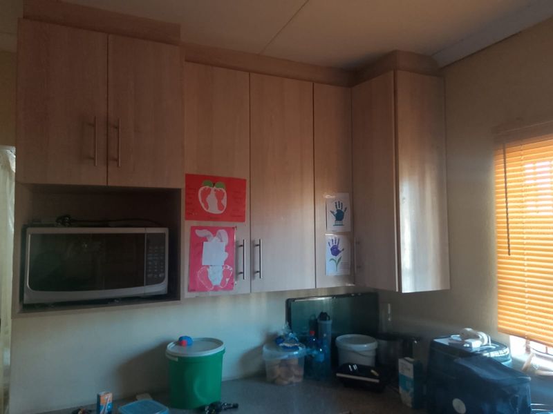 A kitchen area featuring light wood-finish built-in cabinetry with integrated microwave storage and window blinds.