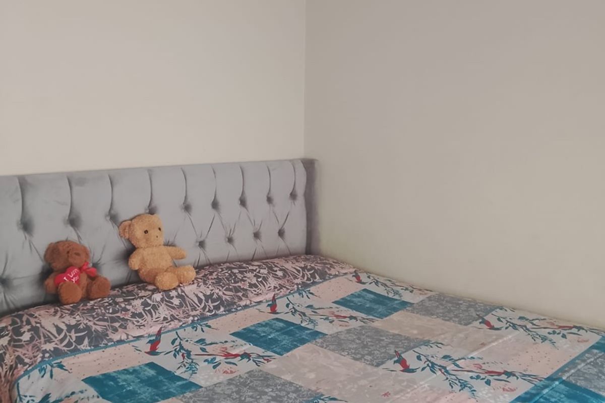 A simple bedroom featuring a tufted upholstered headboard and neutral wall finishes.