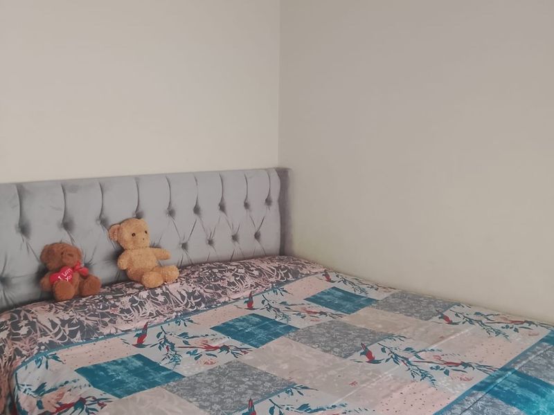 A simple bedroom featuring a tufted upholstered headboard and neutral wall finishes.