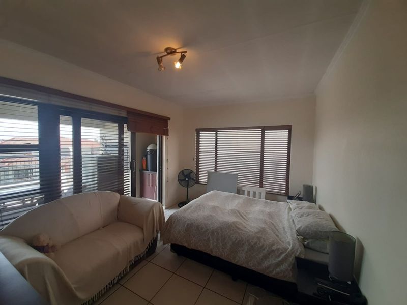 A bedroom featuring tiled flooring, venetian blinds, and a sliding door providing access to an outdoor area.