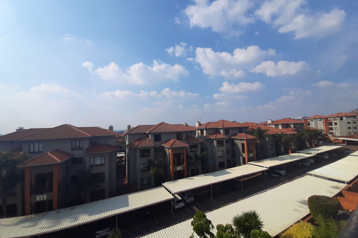 An elevated aerial view of a residential apartment complex featuring multiple buildings with tiled roofs and covered parking bays.