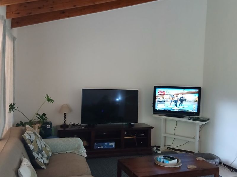 A cozy living room featuring a high vaulted ceiling with exposed timber beams, providing a spacious and rustic architectural feel.