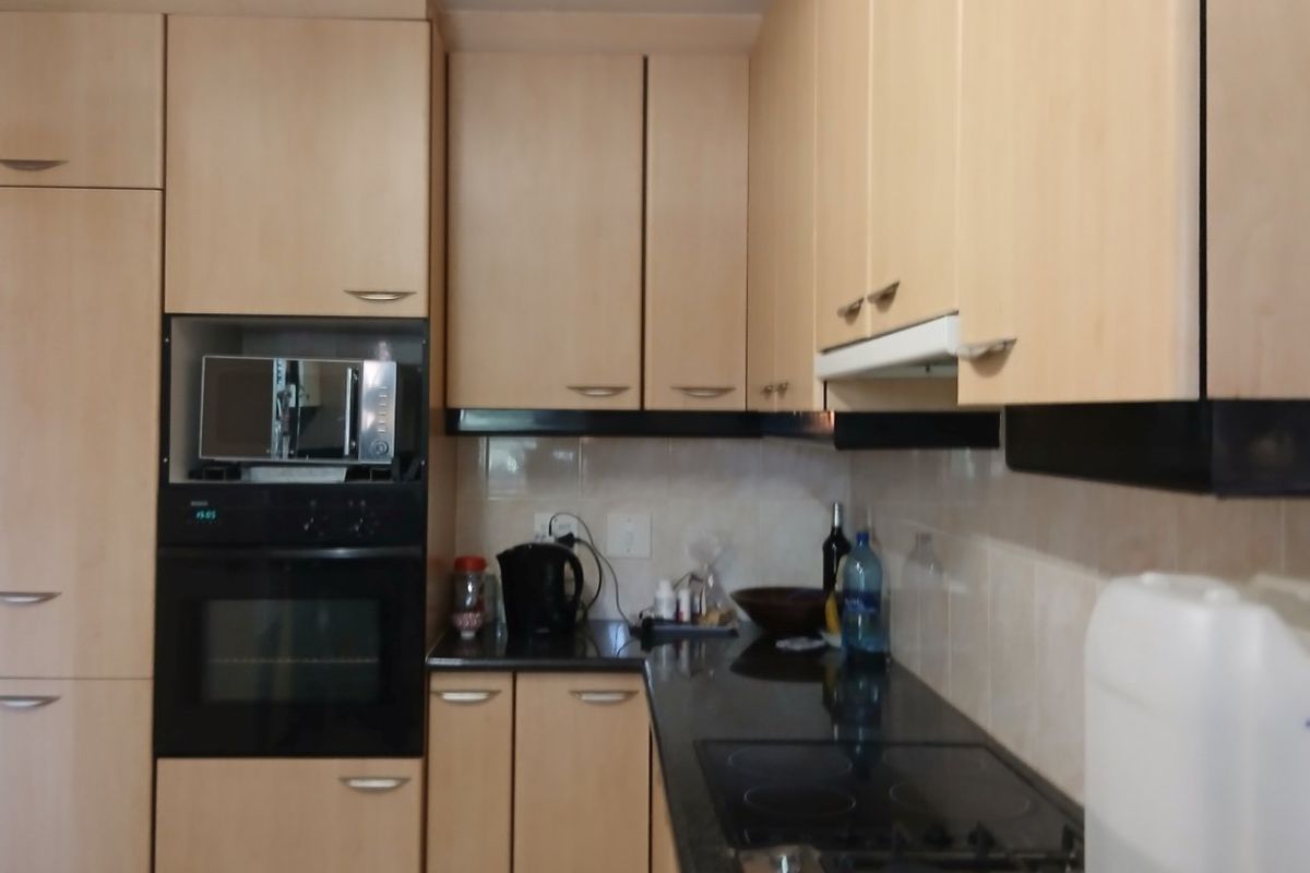 A functional kitchen featuring light wood-tone cabinetry, granite countertops, a built-in oven, microwave, and a gas cooktop with an integrated extractor fan.