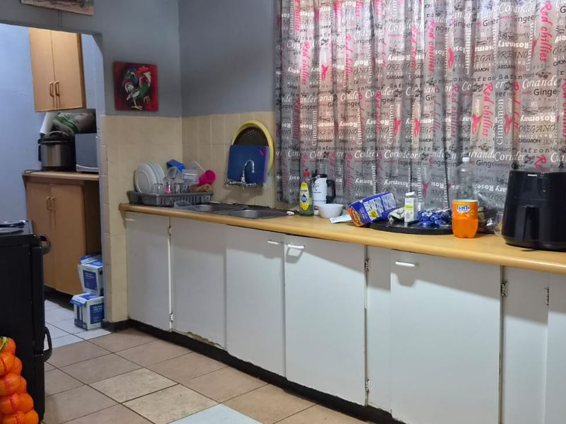 A functional kitchen featuring built-in cabinetry, laminate countertops, and a double bowl sink with tiled backsplash and flooring.