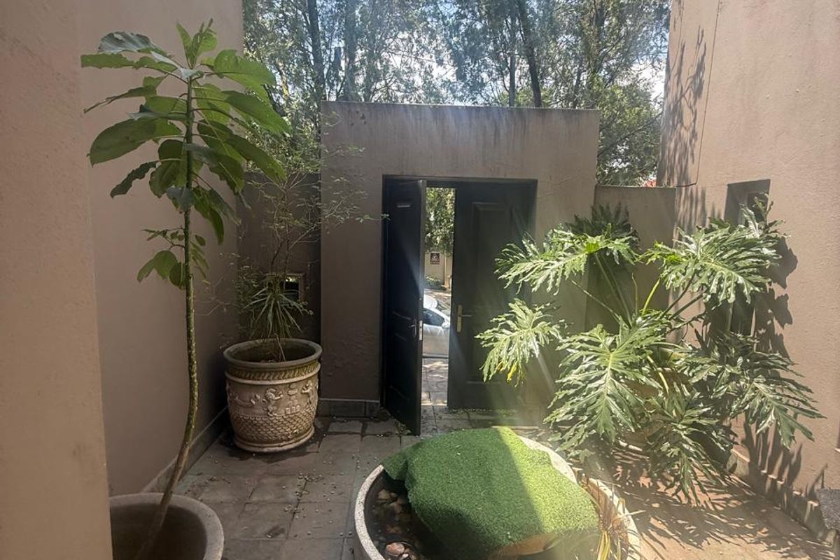 A private paved courtyard featuring a central water feature and double door access, offering a quiet outdoor space between building wings.