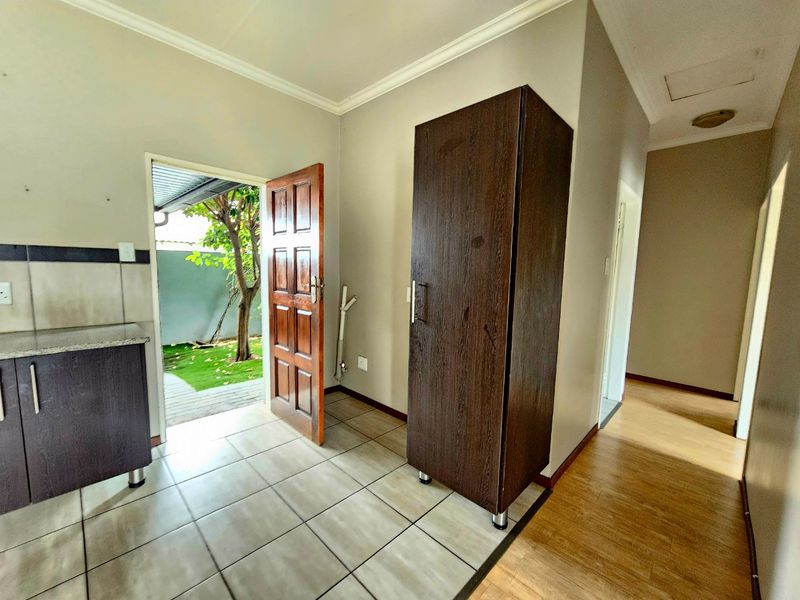 A functional kitchen area featuring tiled floors, built-in cabinetry with granite countertops, and direct access to the outdoor garden space.