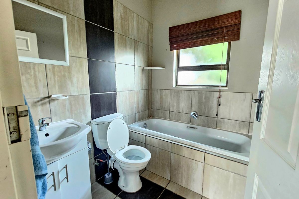 A functional bathroom featuring a bathtub, toilet, and vanity cabinet with tiled wall and floor finishes.