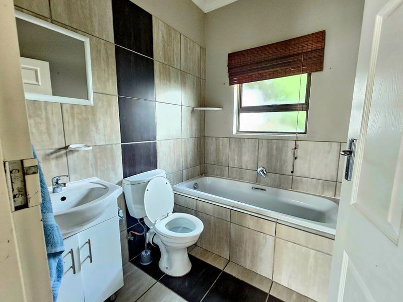 A functional bathroom featuring a bathtub, toilet, and vanity cabinet with tiled wall and floor finishes.