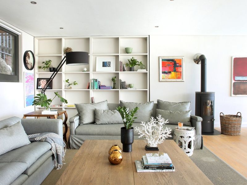 A bright living room featuring timber flooring, built-in shelving, and a modern wood-burning stove, creating a warm and inviting atmosphere.