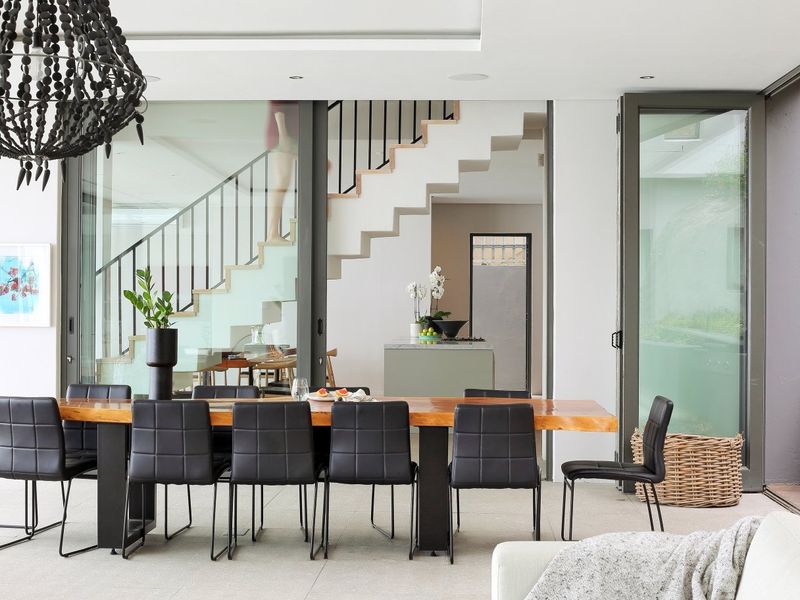Modern open-plan dining area featuring a sleek staircase, large sliding glass doors, and high-quality finishes throughout this contemporary living space.