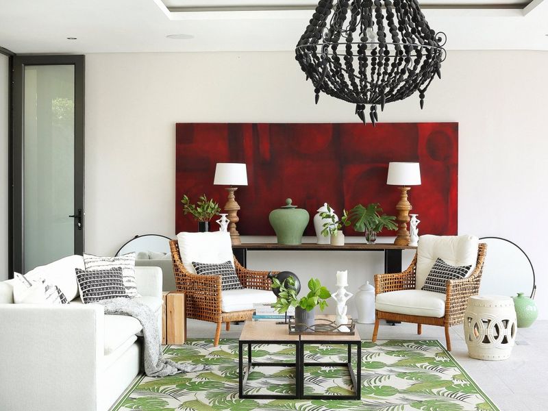 A bright and modern living room featuring tiled flooring, recessed ceiling lighting, and large glass doors leading to an outdoor area.