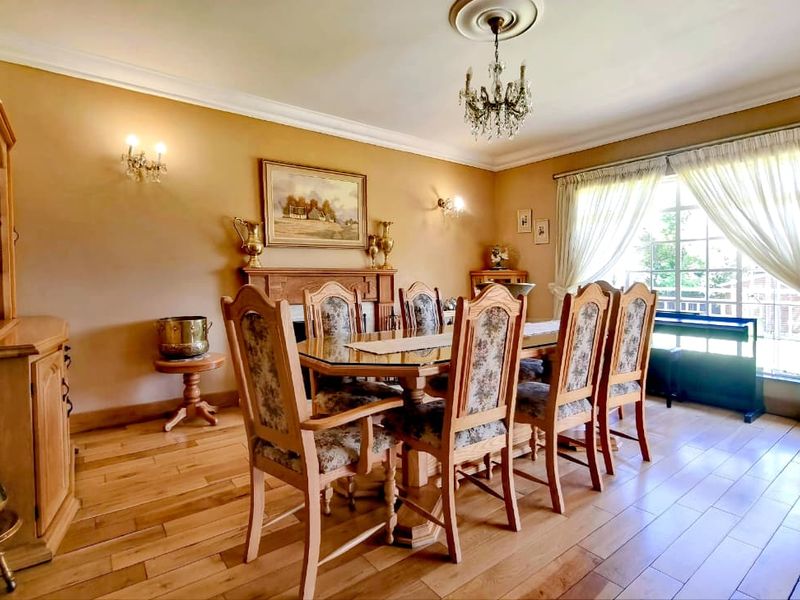 A traditional dining room featuring hardwood flooring, a fireplace mantel, crown molding, and a classic chandelier, offering a warm and formal atmosphere.