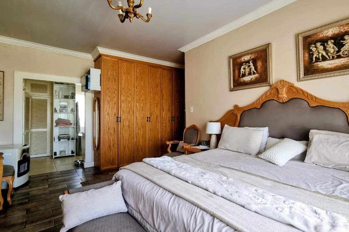 Spacious bedroom featuring built-in wooden cabinetry, crown molding, and tiled flooring, offering a classic aesthetic with ample storage space.