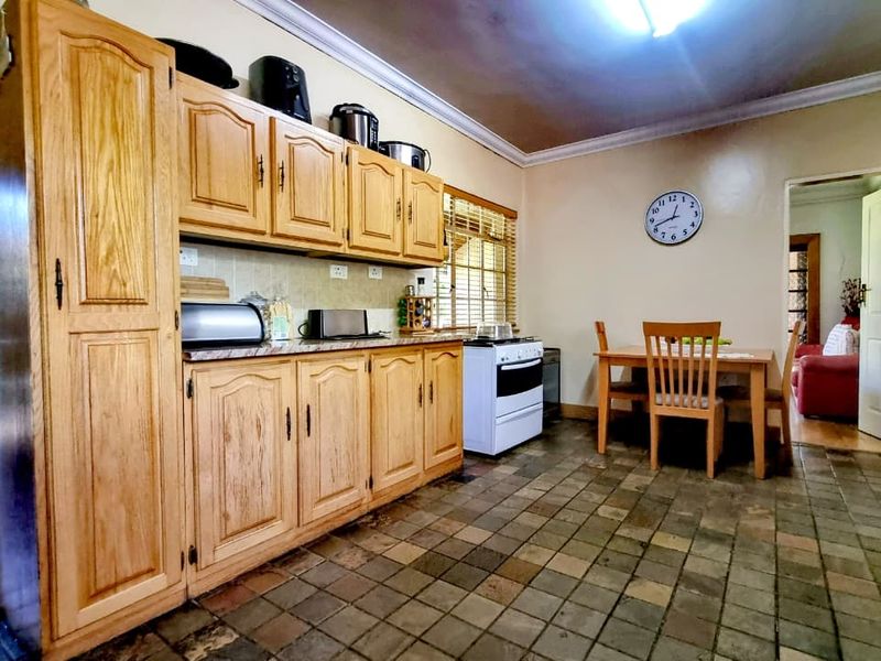 A functional kitchen featuring traditional wooden cabinetry, stone tile flooring, and a freestanding stove, offering a classic layout with potential for modern updates.