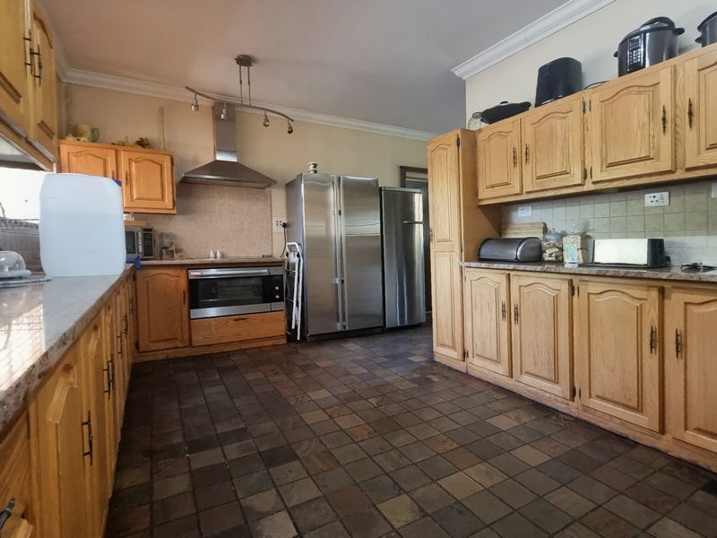 A spacious kitchen featuring traditional wooden cabinetry, granite countertops, tiled flooring, and built-in stainless steel appliances.