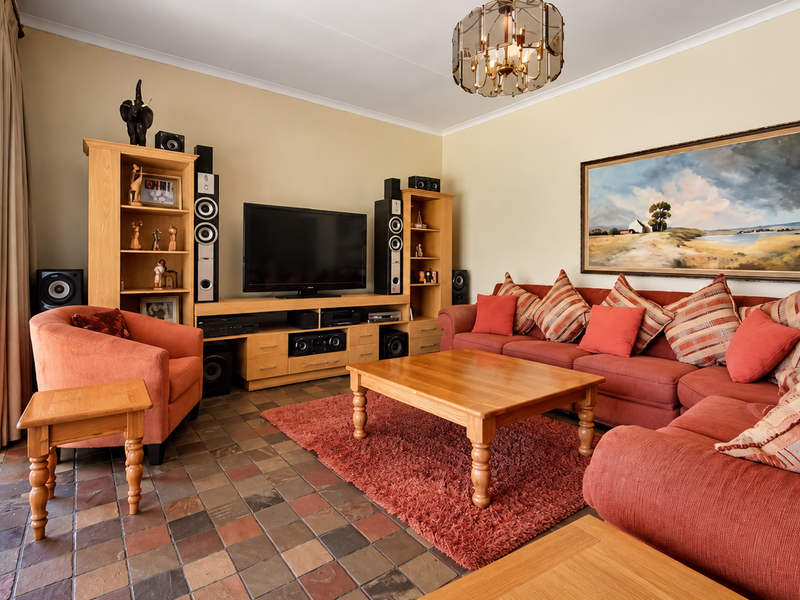 A comfortable living room featuring slate tile flooring, a decorative chandelier, and a security gate leading to the exterior.