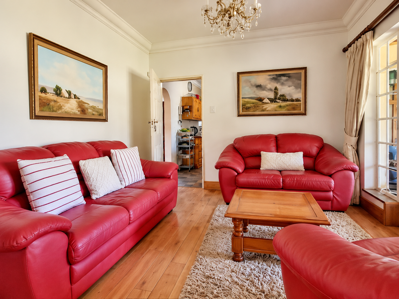 A well-maintained living room featuring hardwood flooring, crown molding, and classic french doors leading to an outdoor area.
