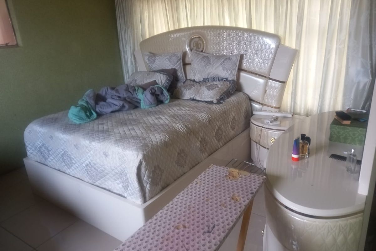 A bedroom featuring tiled flooring and window curtains.